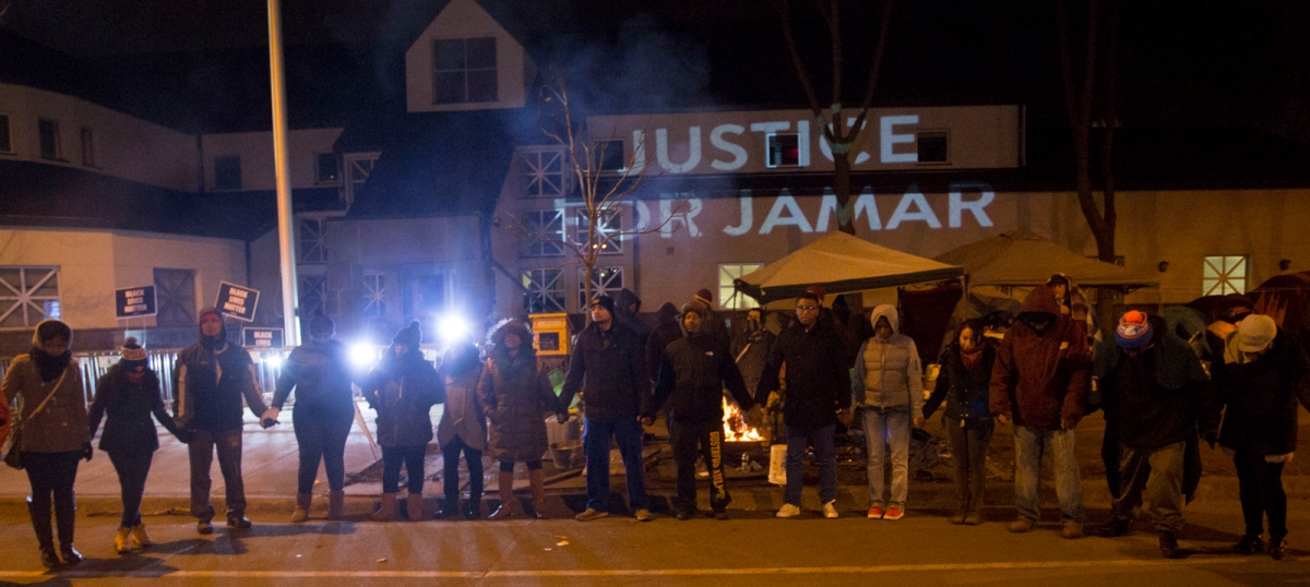 People gather in front of a "Justice for Jamar" projection on side of the 4th police precinct building in North Minneapolis, November 20, 2015